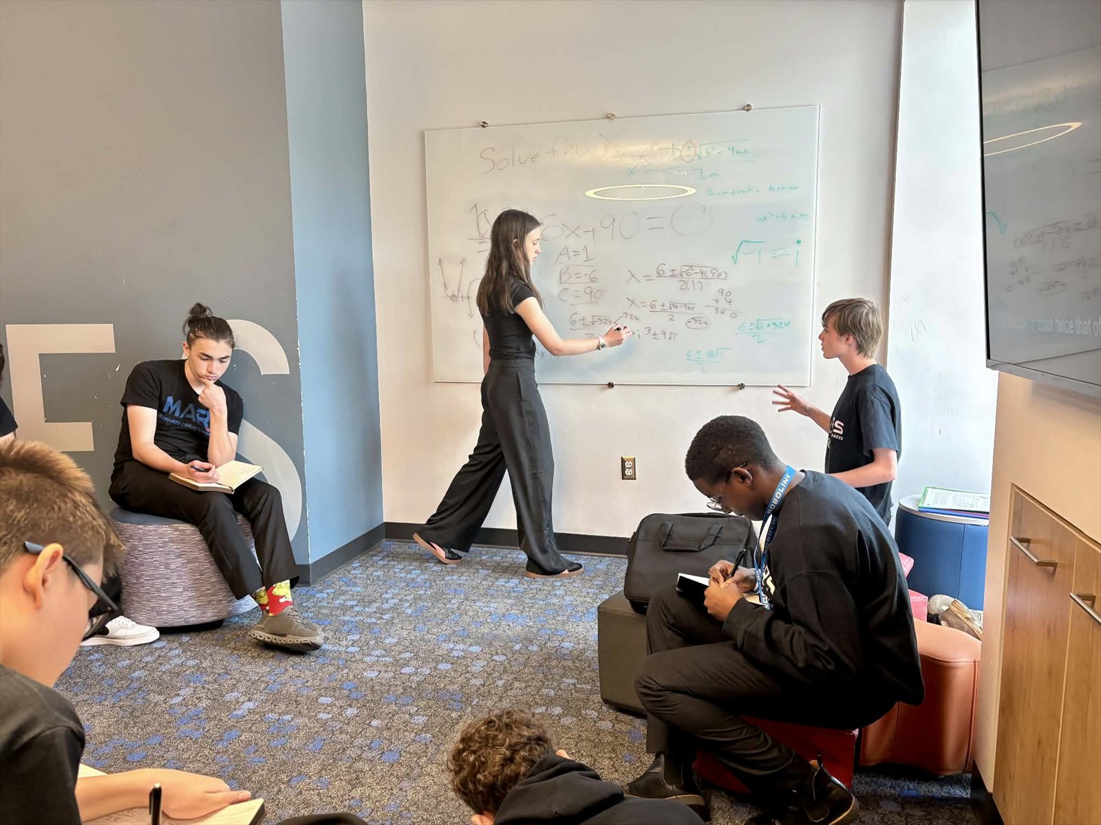MARS students solving a math problem together at a classroom whiteboard.